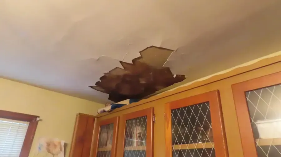 Hole in a water-damaged ceiling above kitchen cabinets, ceiling leak in Loveland, CO
