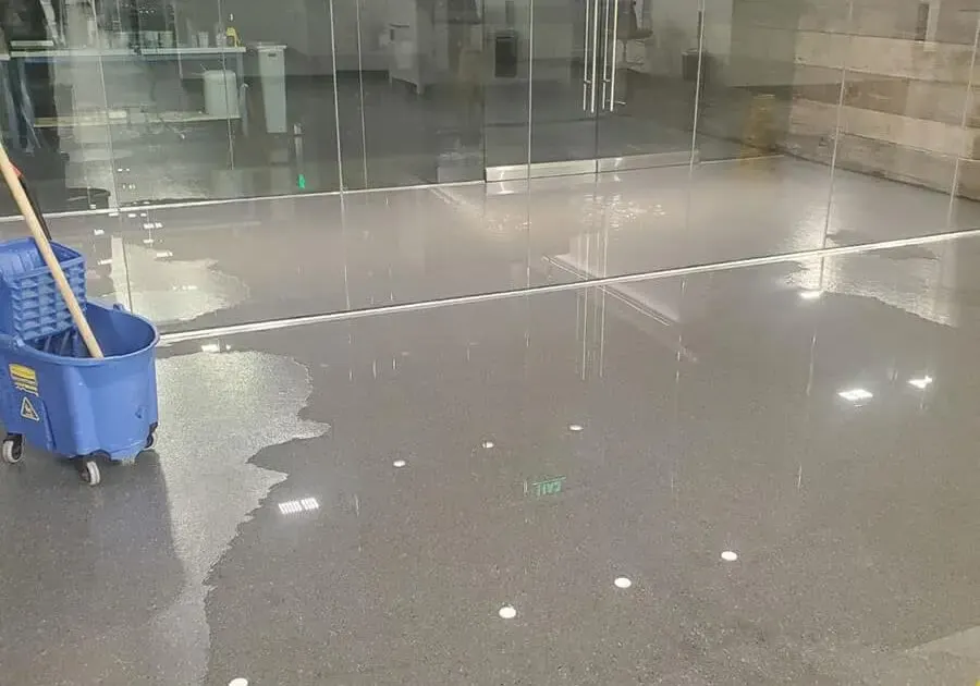 Standing water across an office floor beside a mop bucket, commercial water damage in Loveland, CO