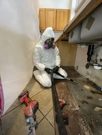 Technician in protective suit and respirator working inside containment, sewage cleanup in Loveland, CO