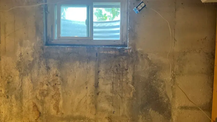 Water-stained basement wall below a window well, window well flooding in Loveland, CO